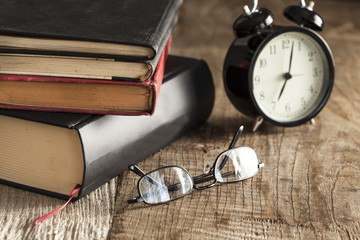 Pile of books with reading glasses on desk