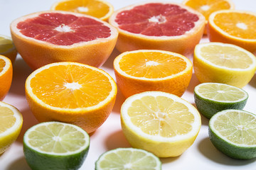 Fototapeta na wymiar Cut citruses of different colors isolated on white. Sliced lemon, orange, lime and grapefruit