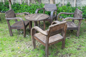 Old wooden chairs and round table in small garden