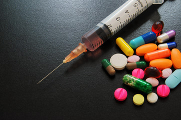 Drugs and syringe on wooden table with room for text, medical concept.