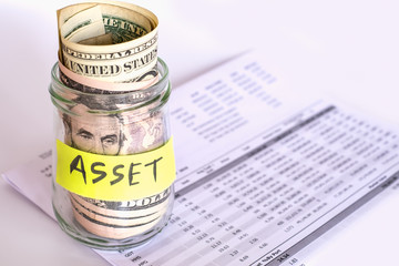Saving and Investment concept. US Dollar bank notes in glass jar place on investment statement.