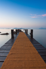 Fototapeta na wymiar Sunrise on the beach.Wooden pier in Romazzino, Sardinia, Italy