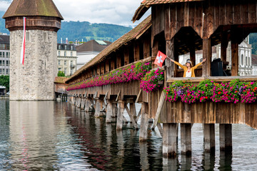 View on the old wooden bridge with young female traveler in Lucerne city in Switzerland