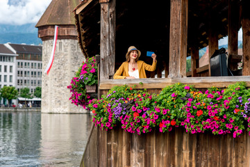 View on the old wooden bridge with young female traveler in Lucerne city in Switzerland