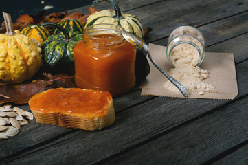 Bread, pumpkin jam, pumpkins and sugar on vintage table. Selective focus and small depth of field.