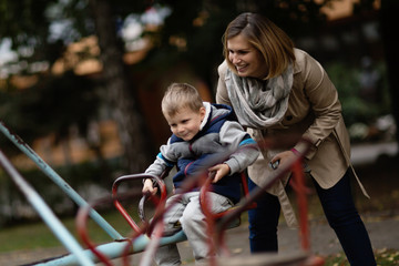 Obraz premium Mother playing with son on caraousel