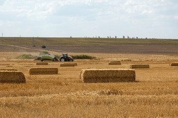 Fototapeta premium Tractor with wheat straw baler. Agricultural background