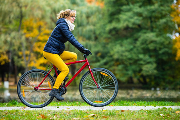 Obraz premium Urban biking - woman riding bike in city park 