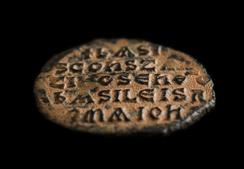 Ancient copper coin in red patina with text on it