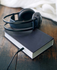 Books and headphones on wooden surface grunge. Concept of listening to audiobooks.