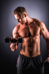 Fototapeta na wymiar Muscular man working out doing exercises with dumbbells at biceps