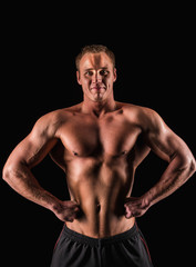 Fototapeta na wymiar Sporty and healthy muscular strong man isolated on black background