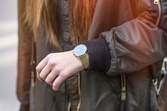 fall fashion outfit. detail shot of a young fashionable woman in a oversized bomber jacket with golden watch on hand

