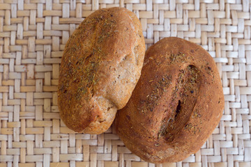 Home baked whole rye bread loaf. Fresh round shape fragrant bread lying on a wicker table made of...