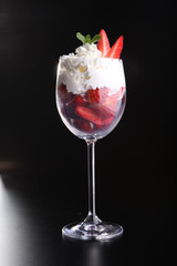 Strawberries and whipped cream in glass.