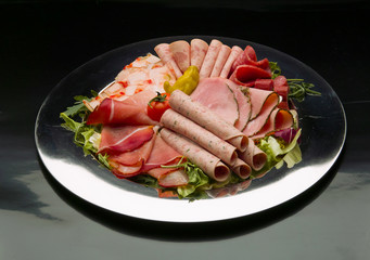 Food tray with delicious salami, pieces of sliced ham, sausage, tomatoes, salad and vegetable - Meat platter with selection