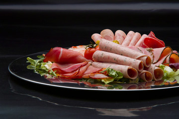 Food tray with delicious salami, pieces of sliced ham, sausage, tomatoes, salad and vegetable - Meat platter with selection
