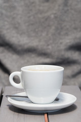 detail shot of a white coffee cup on a grey wooden table. space for text, copy and lettering.

