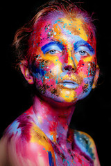 Portrait of a woman with colorful paint brushstroken on face. Bright blue eyes. Advertising Space