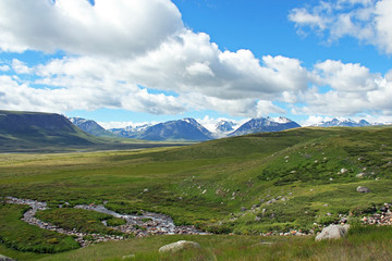 Clouds over snow covered mountains and glacier and river in vall