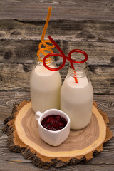 Two bottles of milk with a straw, jam on cutting the tree