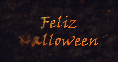 Feliz Halloween text in Spanish dissolving into dust to left.