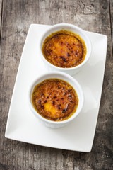 Traditional French creme brulee dessert with caramelized sugar on top, on wooden table


