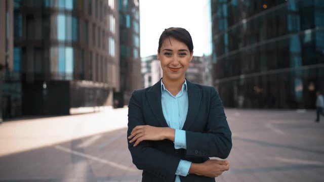 4k. Ultra HD. Portrait of young sexy pretty confident caucasian businesswoman with arms crossed, looking at camera straightens hair and smiling. Pomade, brownhair, lady Success concept. Glossy