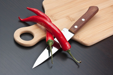 Two red cayenne and knife on the kitchen table