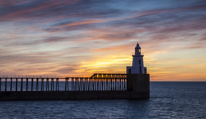 Dawn, Sunrise at Blyth Piers in Northumberland, England, UK. With anglers fishing from pier end.