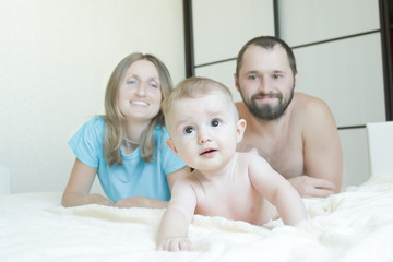 Indoor family portrait of happy parents with their crawling baby