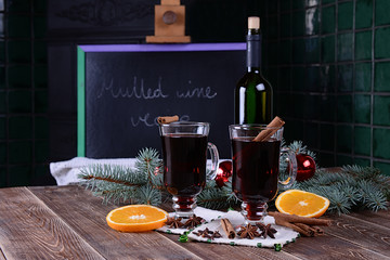 Two glasses of hot mulled wine with apple,orange and spices on a background of traditional...