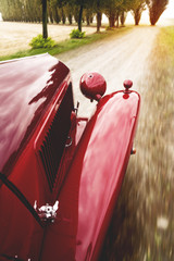 Red vintage car running on a country road at sunset. Immersive point of view. Travel and speed concept.