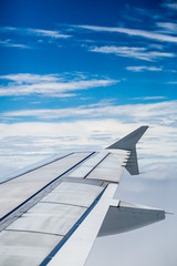 view from the airplane window flying above the clouds, selective forcus at the end of wing