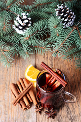  A glass of hot mulled wine with apple,orange and spices on a background of traditional Christmas decorations.