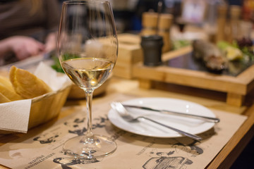 a glass of white wine on a table in a cafe