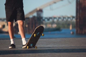 Guy with skateboard outdoor. Legs of skateboarder standing. Sport of young and fearless. For those...