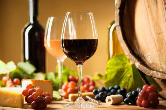 Wine bottle, glasses, cheese, grapes and barrel 