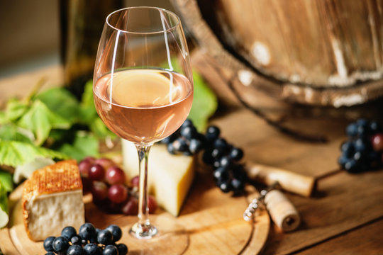 Wine glass, cheese, grapes and barrel 
