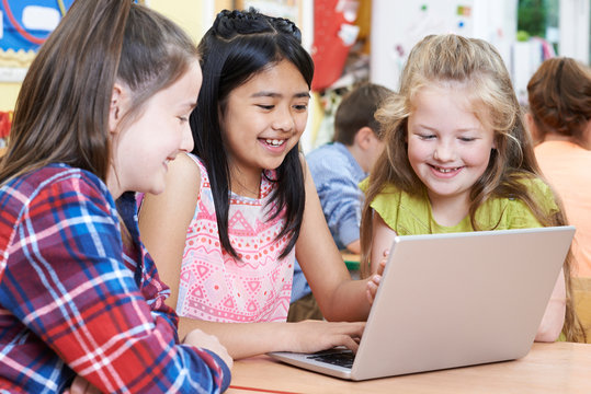 Group Of Elementary School Children Working Together In Computer