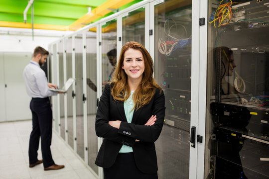 Technician standing with arms crossed in a server room