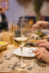 a glass of white wine on a table in a cafe with a blurred backgr