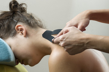 Obraz na płótnie Canvas Physiotherapist putting on black kinesio tape on woman patients