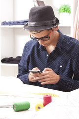 young man in fashion textile shop with mobile phone