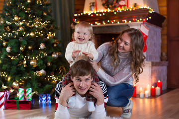 Fototapeta na wymiar christmas, x-mas, family, people, happiness concept - happy parents playing with pretty baby