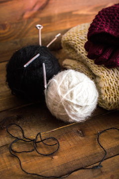 A pair of balls of knitting yarn with spokes. Knitted gloves and sweater. On a wooden background.
