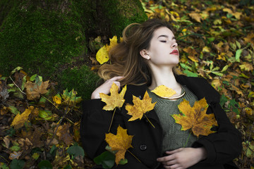 young beautiful girl in the middle of autumn leaves in the background