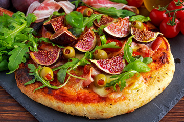 Fig pizza with bacon, green pimiento olives, rocket and basil leaves