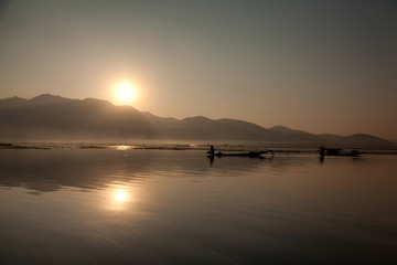 Fototapeta premium Intha fisherman fishing at sunset in his typical canoe with fish