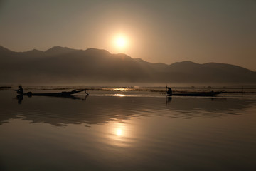 Intha fisherman fishing at sunset in his typical canoe with fish